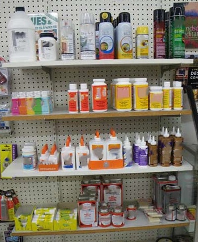 Various art adhesive products on a store shelf.