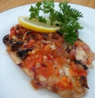 Baked tilapia with tomatoes on a plate.