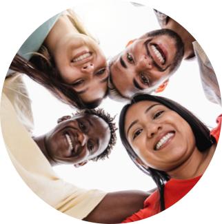 Four people standing in a huddle looking down at the camera.